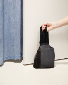 Håndlavet genbrugsdørstopper En person løfter en sort genbrugsdørstopper med en hånd.