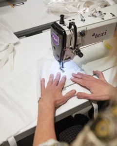 Fra sengetøj til gaveposer En symaskine, hvor en gavepose bliver syet af hvidt stof.