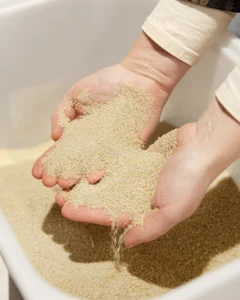 Kalkpellets – et biprodukt fra drikkevandsrensning Hænder holder og lader kalkpellets drysse ned i en beholder.