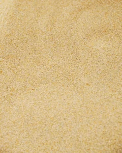 Fintforarbejdede kalkpellets Nærbillede af kalkpellets, der danner en jævn, sandlignende overflade.