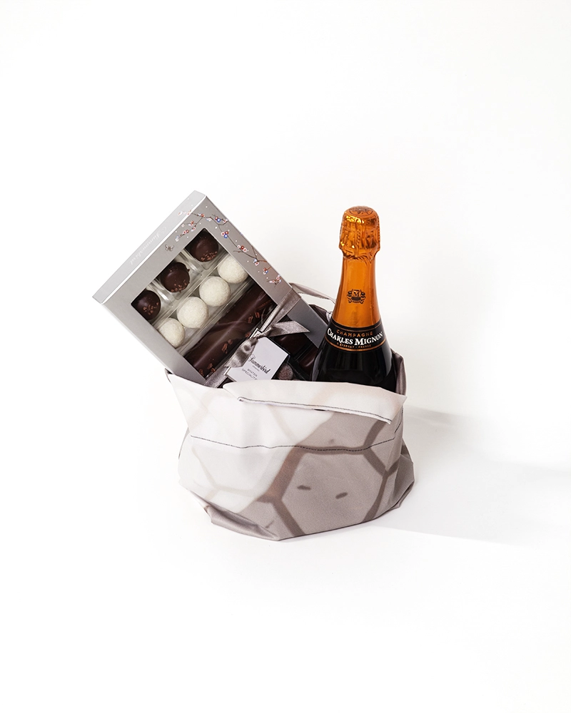 Lille gavepose syet af kasserede tekstiler, fyldt med champagne og chokolade.