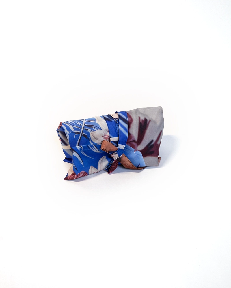 Toilettaske syet af kasseret banner i blå og grå nuancer, sammenrullet og bundet med stofbånd.