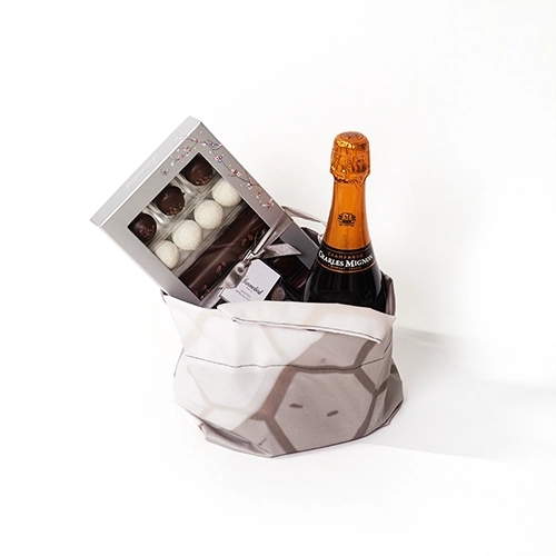 Lille gavepose syet af kasserede tekstiler, fyldt med champagne og chokolade.